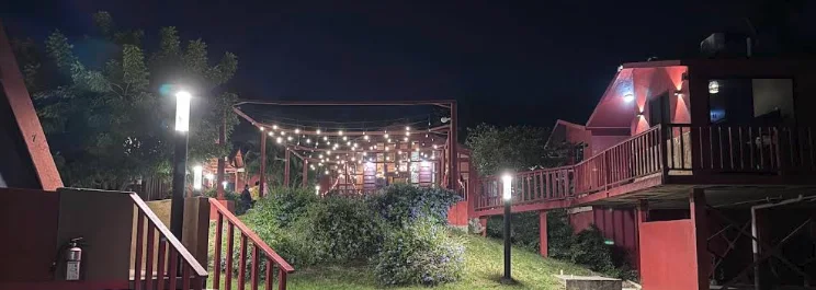 Palapa con luces de serie y cabañas iluminadas por la noche